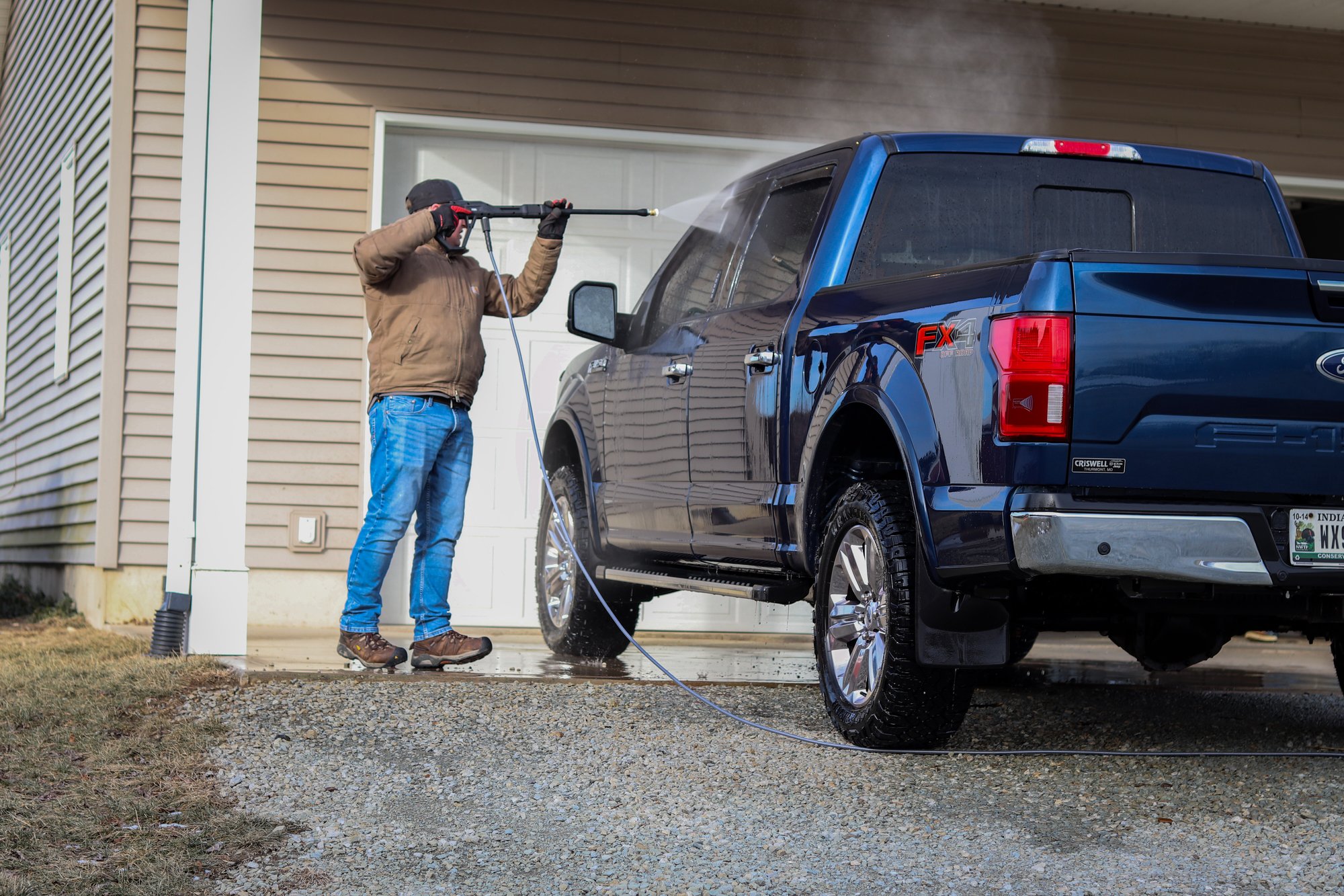 Man spraying water on blue truck.